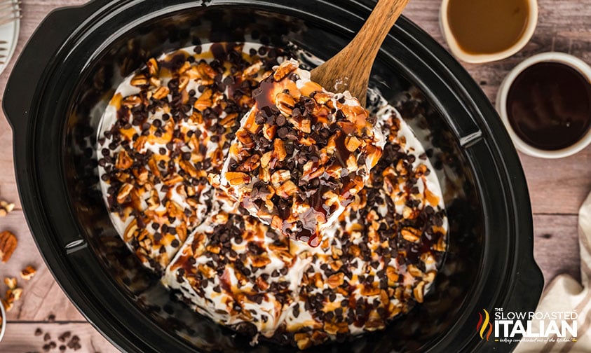 adding chopped pecans and chocolate chips to top of cake in crockpot