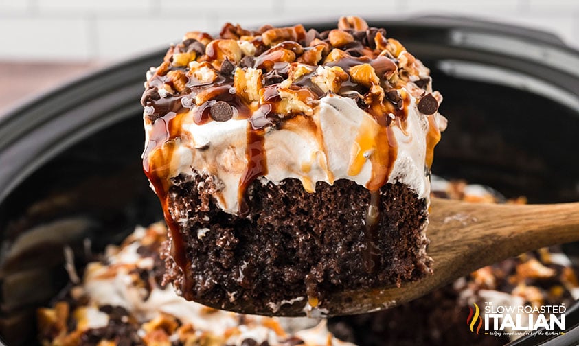 slice of crockpot turtle chocolate poke cake on a wooden spoon