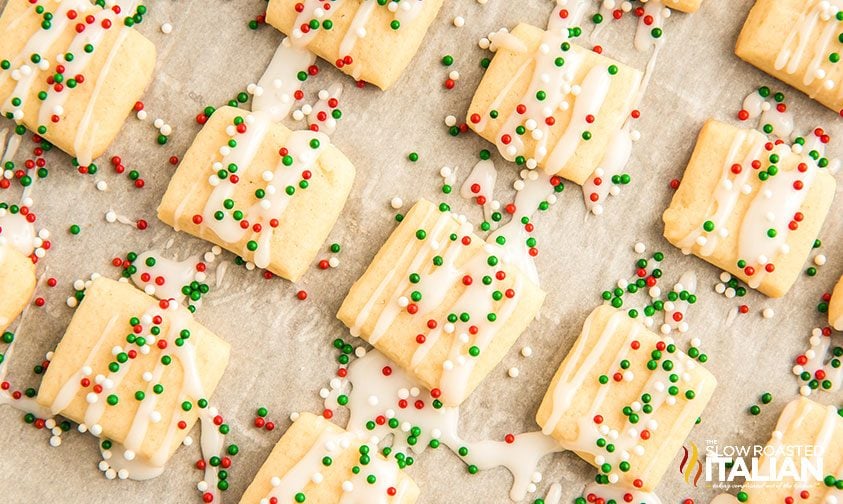 mini frosted sugar cookies with sprinkles on parchment paper