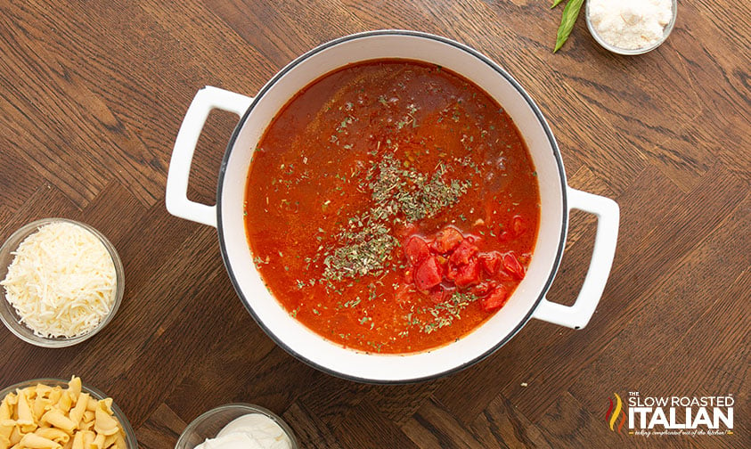 adding tomatoes, paste, sauce, seasonings and onion to pot.