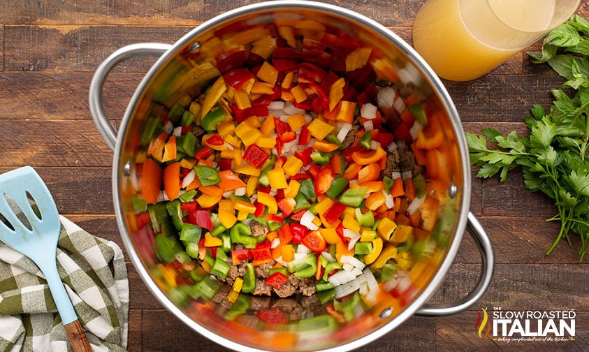 adding diced onions, garlic and chopped peppers to a large pot