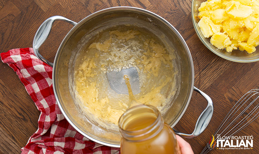 adding chicken stock to large pot