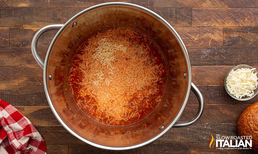 adding shredded cheese to pepperoni soup