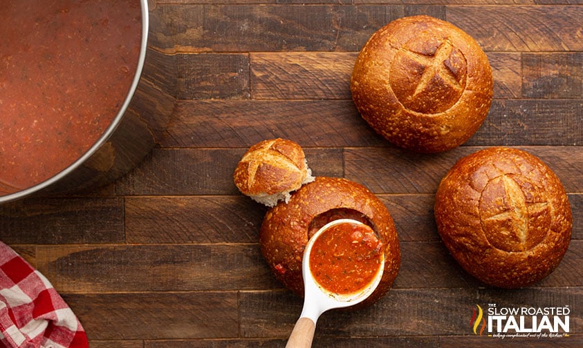 adding pepperoni soup to bread bowls