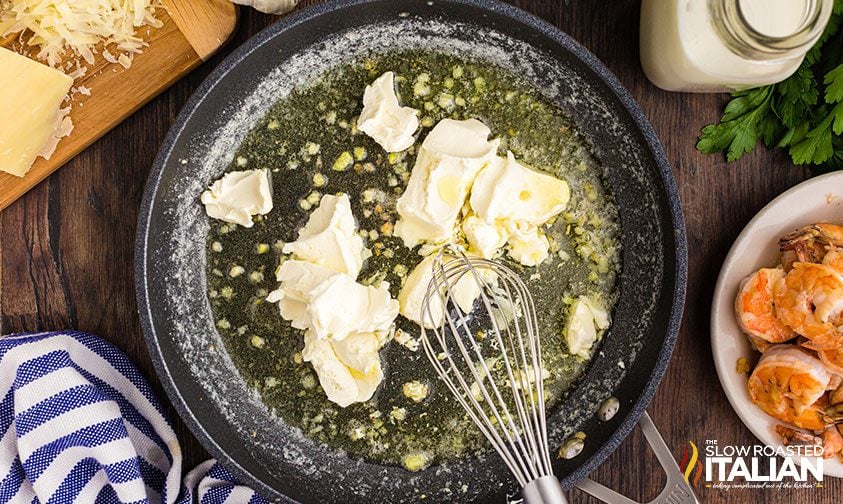 whisking cream cheese with garlic and butter in skillet