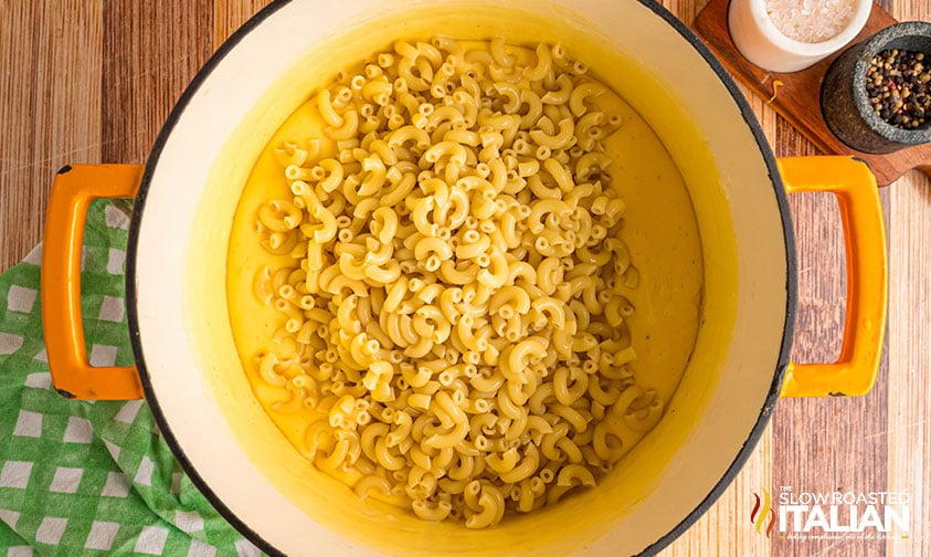 adding macaroni to large pot of creamy 4 cheese sauce