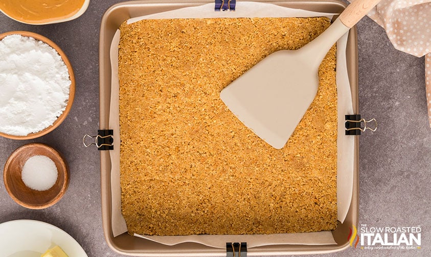 pressing chocolate peanut butter graham cracker bars crust into baking pan