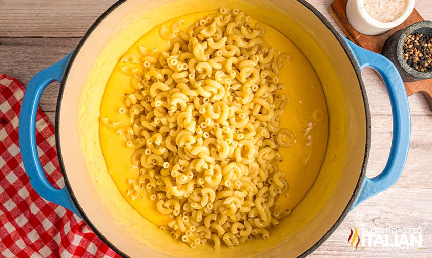 adding cooked pasta to creamy cheese sauce for kfc mac and cheese