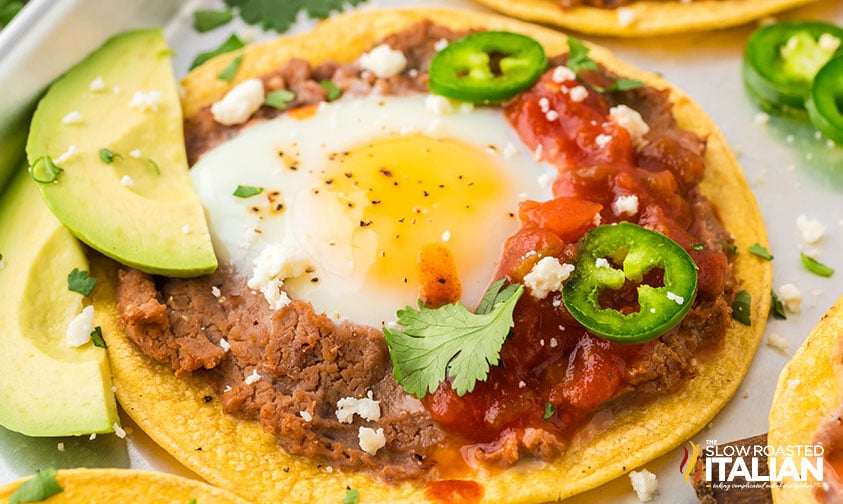 closeup of huevos rancheros with sliced avocado and jalapeno