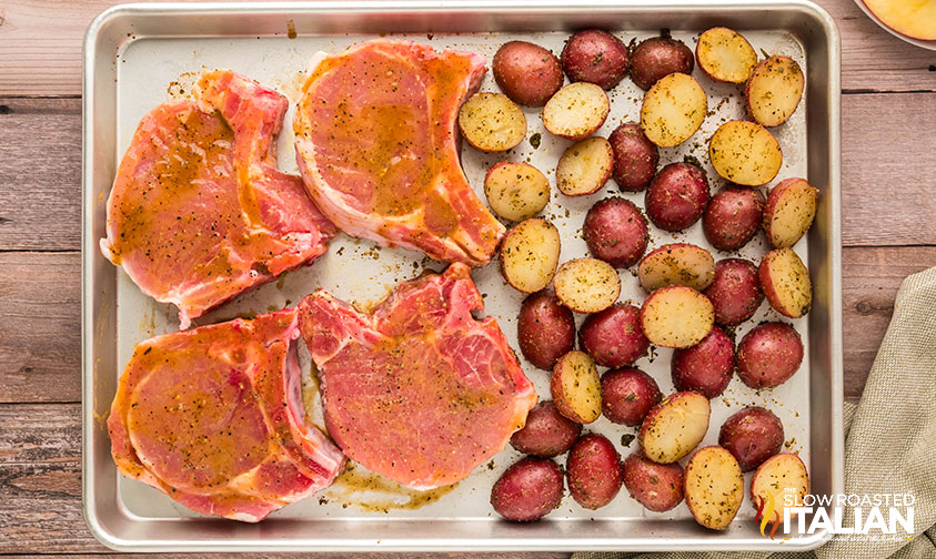 potatoes and pork chops on a baking sheet