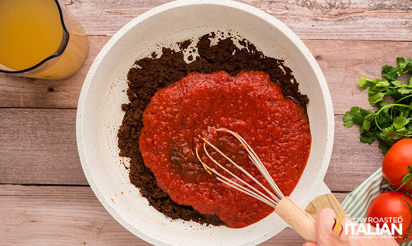 adding pureed tomatoes and chicken stock to skillet