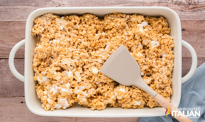 pressing salted caramel rice krispie treats in baking dish