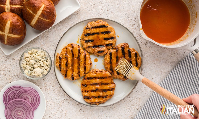 brushing grilled chicken burgers with buffalo sauce