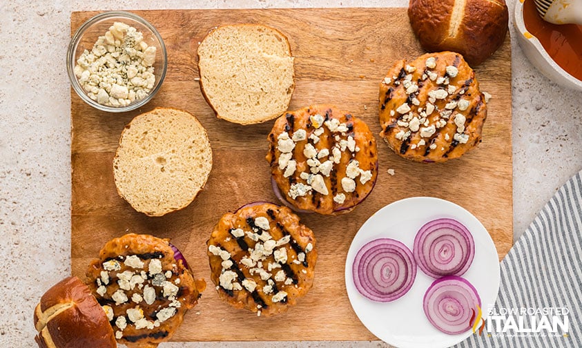 adding topping to buffalo chicken burgers