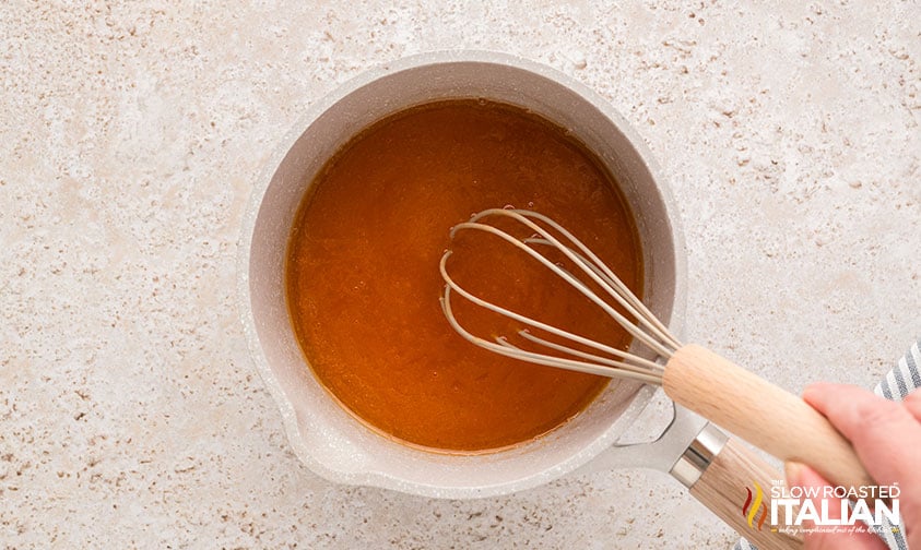 whisking buffalo sauce for chicken burgers in a small pan