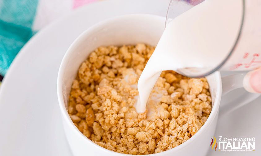 pouring milk into mug of crushed golden oreos