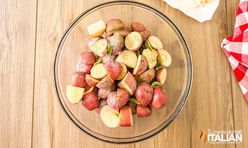 chopped red potatoes in glass bowl with herbs and spices