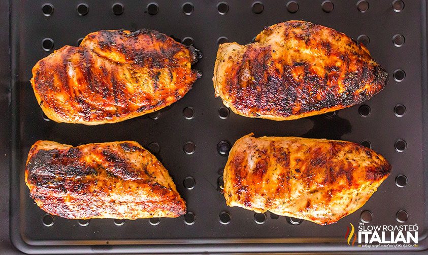 grilled chicken breasts on black tray