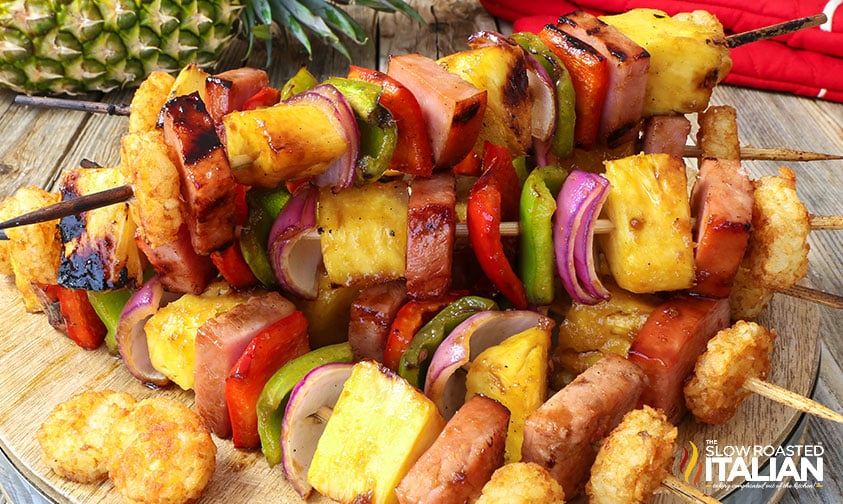 ham and pineapple skewers stacked on round wooden board